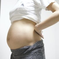 妊娠38週でお腹を出した立ち姿の妊婦様のお写真